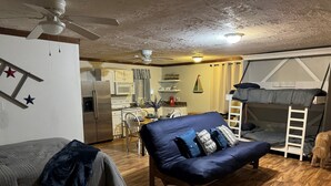 A compact living space with a sofa, a bunk bed, a kitchenette, and a ceiling fan. - The Getaway @ Nolin  (Clarkson)