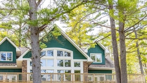 Un chalet doté d’un escalier en pierre menant à une terrasse en bois, le tout entouré d’arbres.