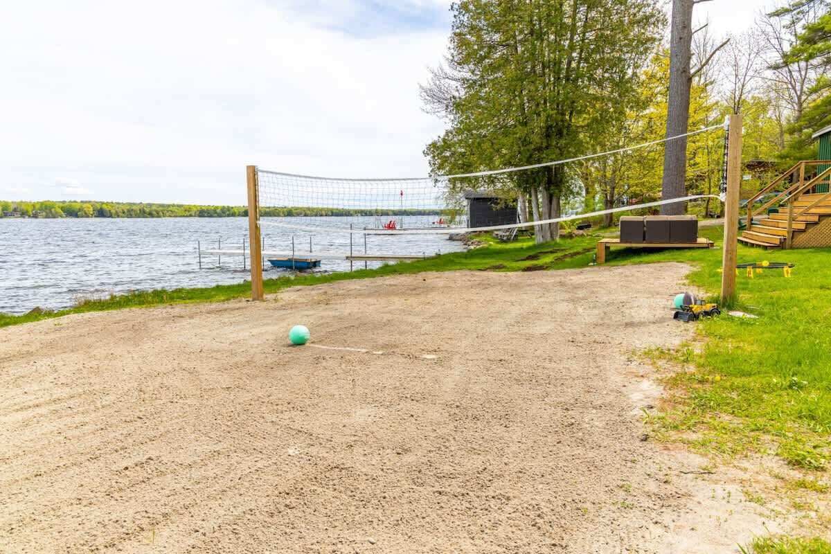 Un terrain de beach-volley avec un filet, un petit abri et un escalier menant à une terrasse.