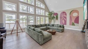 Un salon spacieux avec un grand canapé d’angle, une table basse et un trépied.