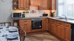 Una cocina con armarios de madera, microondas, tostadora y pileta.