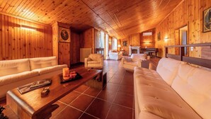 A spacious, wooden-furnished living area with multiple sofas and a fireplace. - Villangelo - Camera Matrimoniale (Aiello del Sabato)