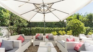An outdoor patio area with wicker furniture and a large umbrella. - Villangelo - Camera Matrimoniale (Aiello del Sabato)