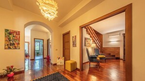 A spacious hallway with wooden flooring, a black textured rug, and a staircase leading to another room. - Villangelo - Camera Matrimoniale (Aiello del Sabato)
