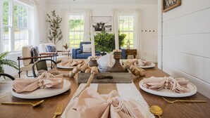 A dining room with a wooden table set for a meal, featuring plates, napkins, and cutlery. - Newly Built Home! 5 Minutes to Pigeon Forge! (Pigeon Forge)
