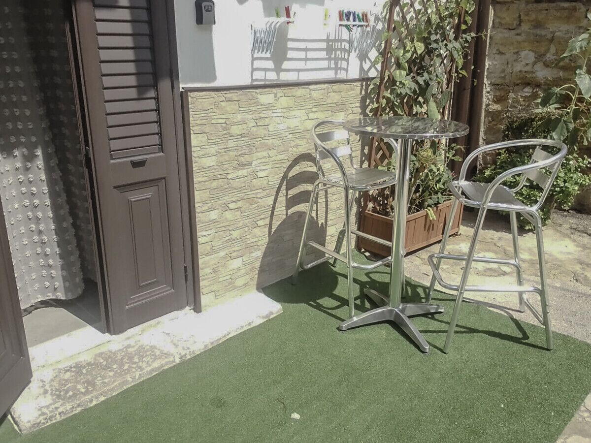 An outdoor seating area with a table and chairs, a door, and a stone wall.