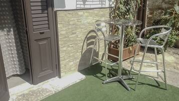 An outdoor seating area with a table and chairs, a door, and a stone wall.