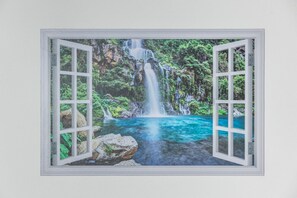 A framed window with a view of a waterfall and a clear blue pool. - The House of Schiu Schiu (Palermo)