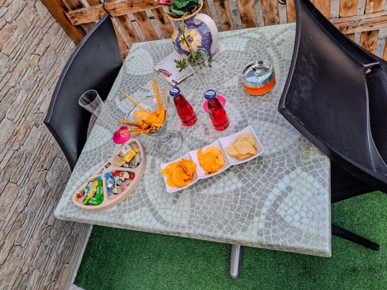 A table with snacks, drinks, and a decorative vase.
