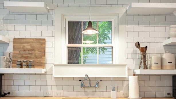 Cocina moderna con armarios blancos, encimera de madera, pileta integrada y ventana con vistas a la vegetación.