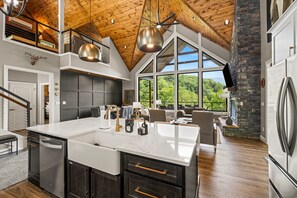 A spacious kitchen with a large island, modern appliances, and a high ceiling with exposed beams.