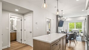 Una cocina moderna con una isla central, armarios de madera e iluminación colgante.