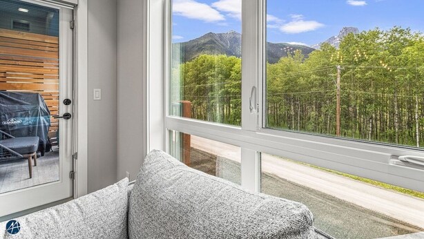 Una habitación con un amplio ventanal que ofrece vistas a un bosque y montañas.
