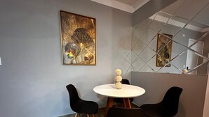 Un comedor moderno con una mesa redonda y cuatro sillas negras. Un jarrón decorativo con objetos esféricos está sobre la mesa.