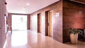 Un moderno vestíbulo de hotel con piso de baldosas pulidas, paneles de madera y una recepción con planta en maceta.