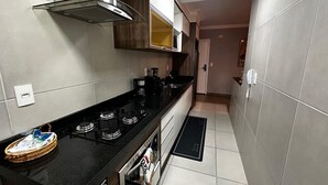 Una cocina moderna con encimera negra, electrodomésticos de acero inoxidable y horno empotrado.