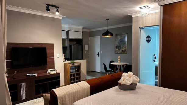 Habitación de hotel con televisor, zona de comedor y puerta con el letrero 'RED'.