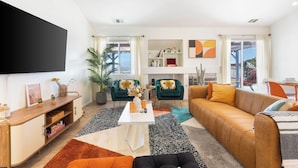 Ein modernes Wohnzimmer mit einer Couch, Sesseln, einem Couchtisch und einem Fernseher.