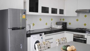 A modern kitchen with stainless steel appliances, a built-in washing machine, and a dining area with a table and chairs.