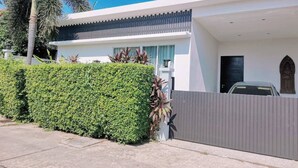 A modern house with a white exterior, a dark roof, and a grey fence.