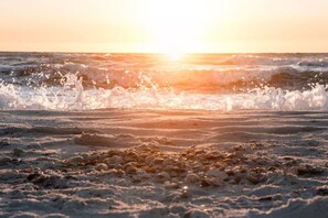 A beach with waves and a sunset.