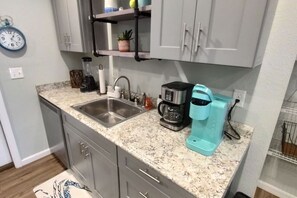 Una cucina con piano di lavoro in granito, lavello in acciaio inossidabile e macchina da caffè.