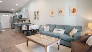 A living room with a sofa, coffee table, and a dining area with chairs and a table.