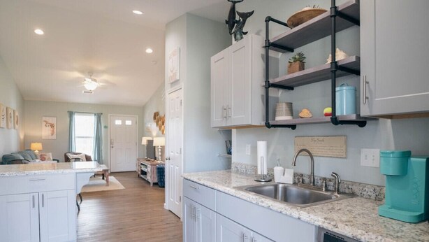 A modern kitchen with white cabinetry, granite countertops, and a built-in dishwasher.