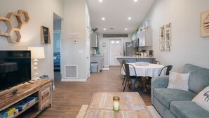 A modern living room with a TV, wooden entertainment unit, and a cozy seating area.
