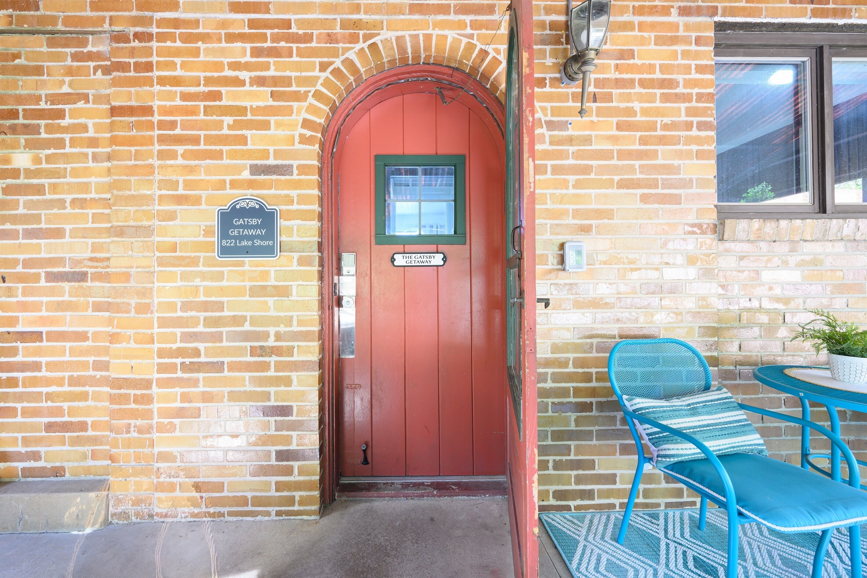 En röd dörr med en skylt som visar texten: "GATSBY GETAWAY 822 LAKE SHORE".