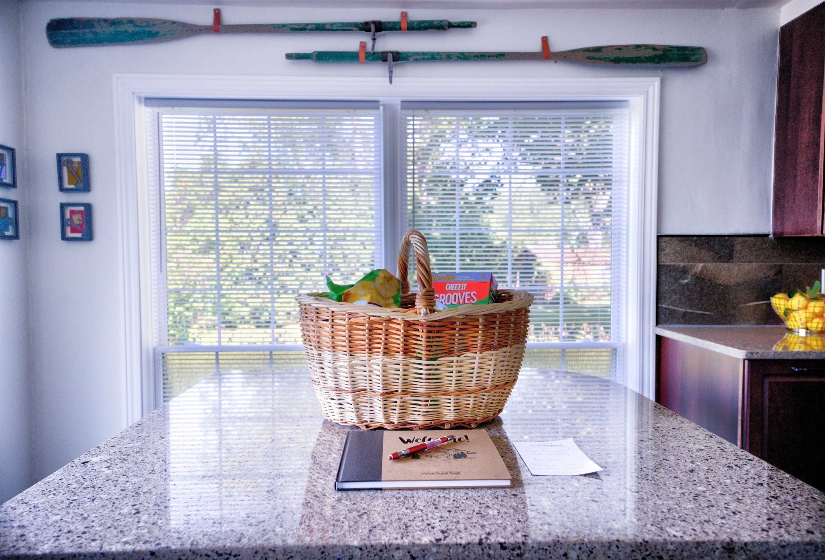 A kitchen counter with a wicker basket containing groceries, a notebook, and a pen.
