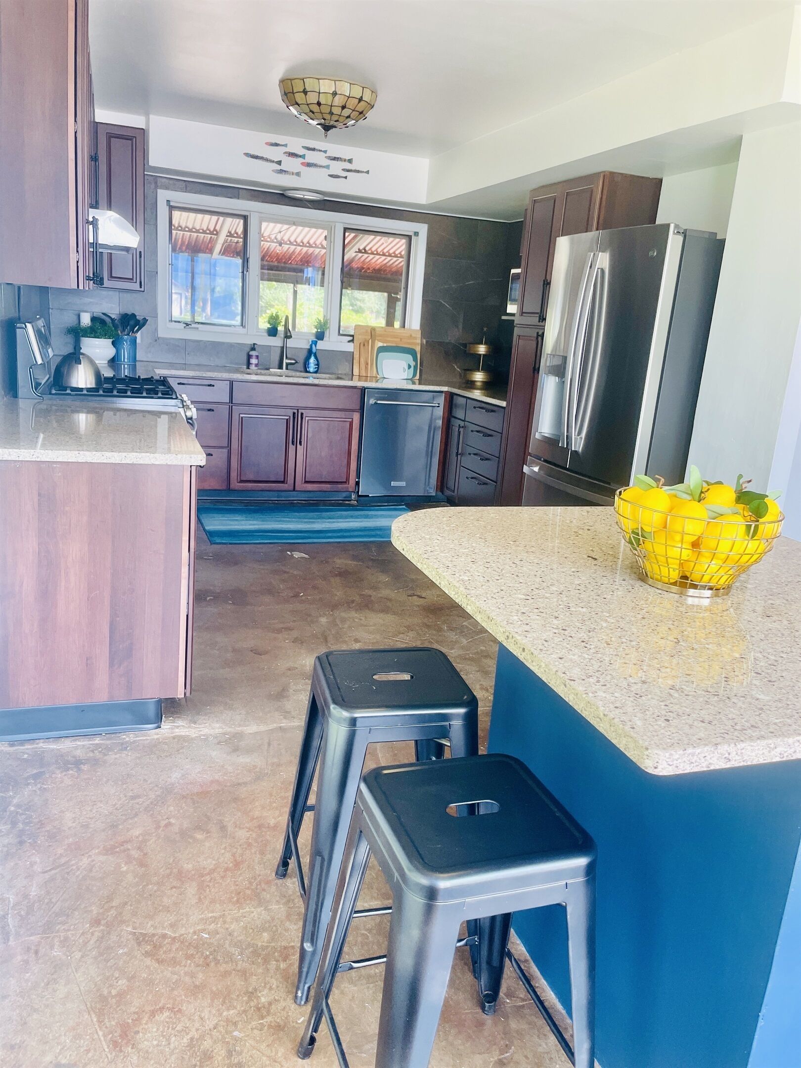 A modern kitchen with dark wood cabinets, stainless steel appliances, and a blue accent wall.