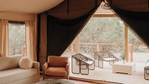 A spacious room with a large window, a sofa, a chair, and a small table. - Lavender - Luxury Glamping Tent (Johnson City)
