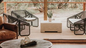 A cozy outdoor seating area with wicker chairs and a round table, overlooking a natural landscape with trees and a clear sky. - Lavender - Luxury Glamping Tent (Johnson City)