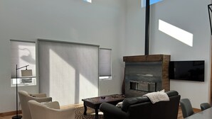 Uma sala de estar moderna com lareira, sofá, mesa de centro e TV na parede.