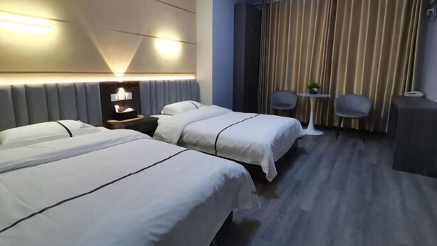 A hotel room with two beds, a desk, a chair, and a curtain. - Dongzhi IKEA Business Hotel (Dongzhi)