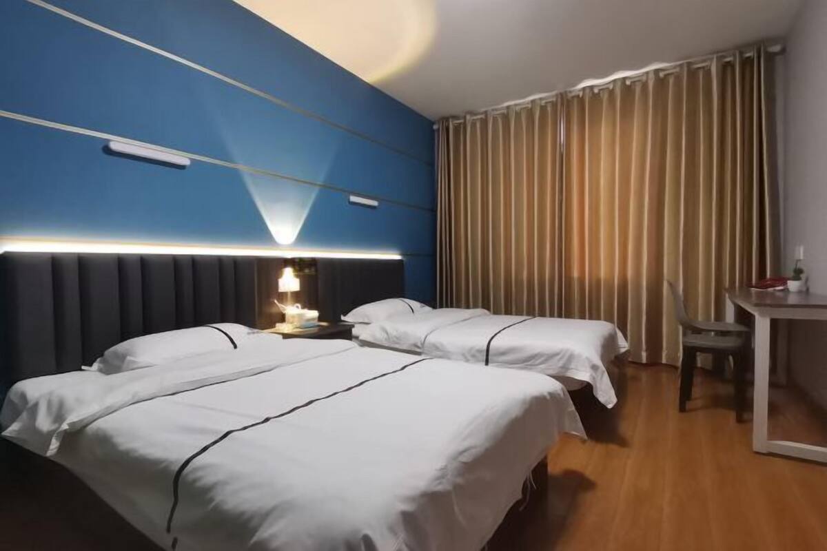 A hotel room with two beds, a desk, and a chair.