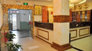 A hotel lobby with a reception desk, a glass door entrance, and a wall with framed items. - Dongzhi IKEA Business Hotel (Dongzhi)