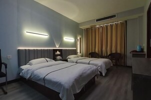 Habitación de hotel con dos camas, un escritorio, una silla y una ventana con cortinas.