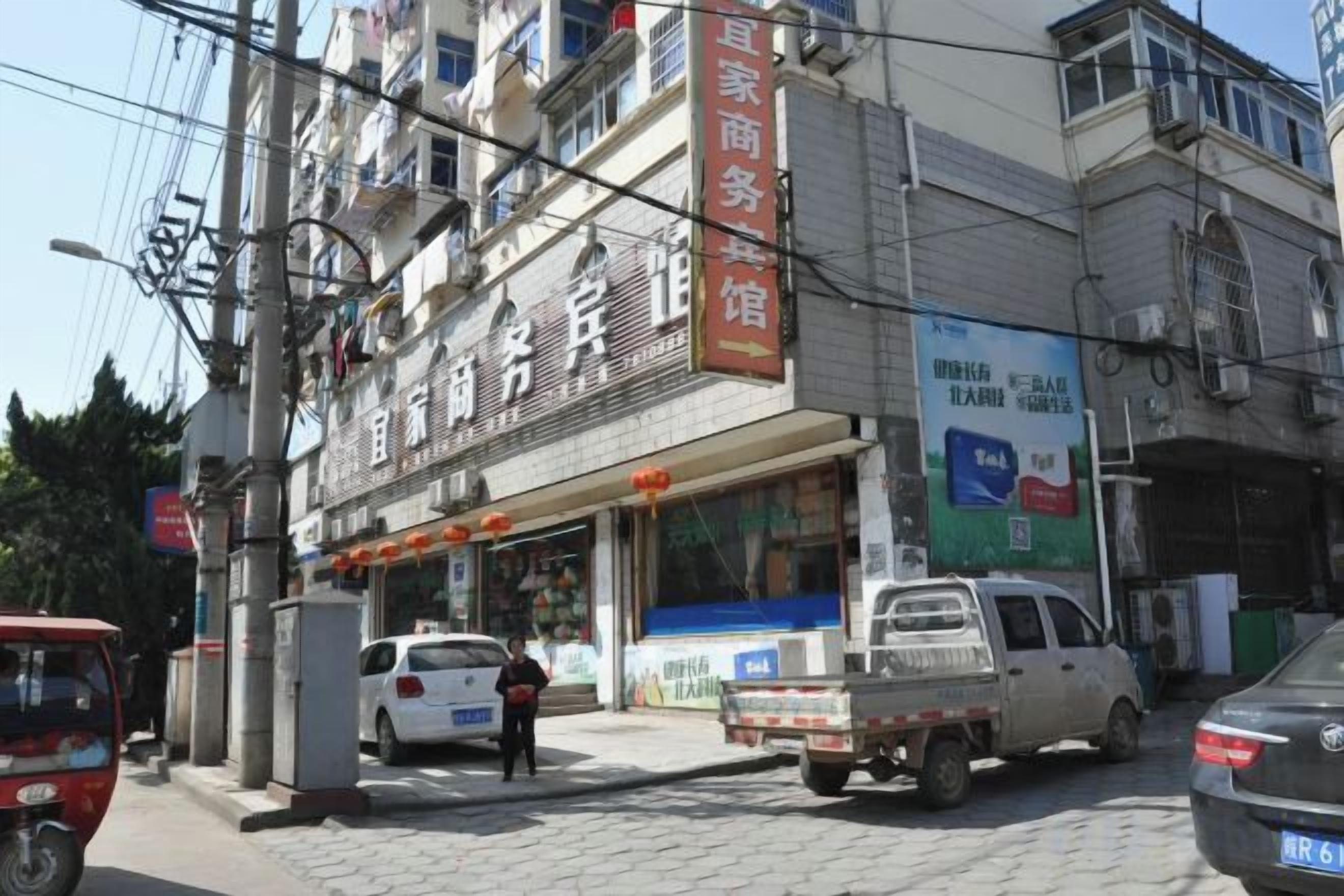 Un edifici comercial amb diverses plantes, una botiga i un vehicle estacionat al davant.
