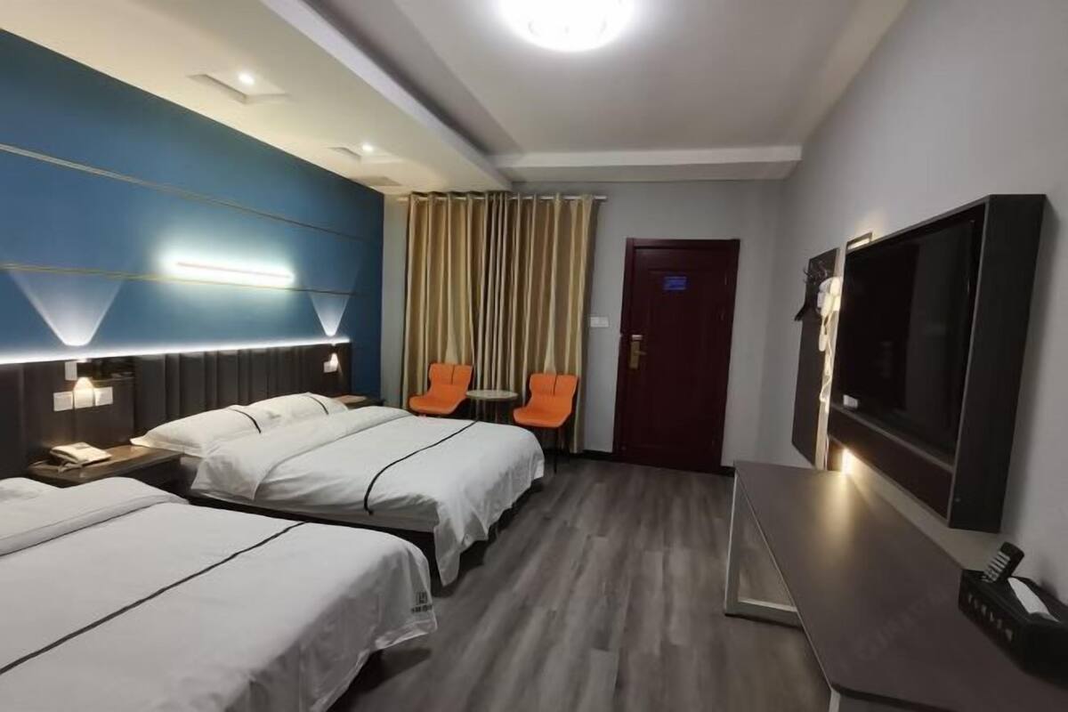 A hotel room with two beds, a TV, a desk, and a small table with chairs.