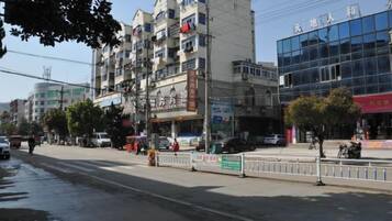 Un edificio de varios pisos con locales comerciales en la planta baja, un paseo peatonal y un cielo despejado.