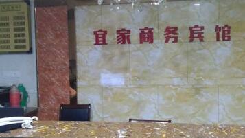 Un área de recepción con pared de mármol y mostrador de recepción.