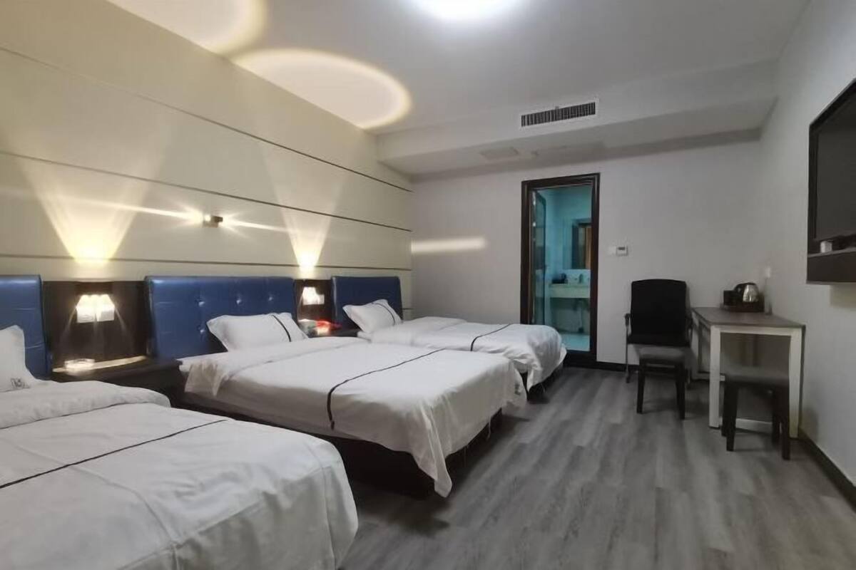 A hotel room with three beds, a desk, and a chair.