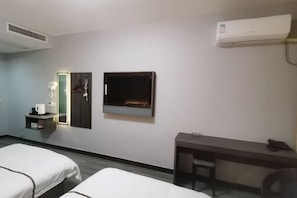 A hotel room with two beds, a desk, a chair, a mirror, a shelf with a kettle, and an air conditioning unit. - Dongzhi IKEA Business Hotel (Dongzhi)