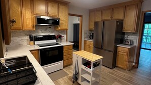 A modern kitchen with wooden cabinets, stainless steel appliances, and a white countertop. - Serene waterfront home at Smith Mountain Lake in Huddleston, VA (Huddleston)
