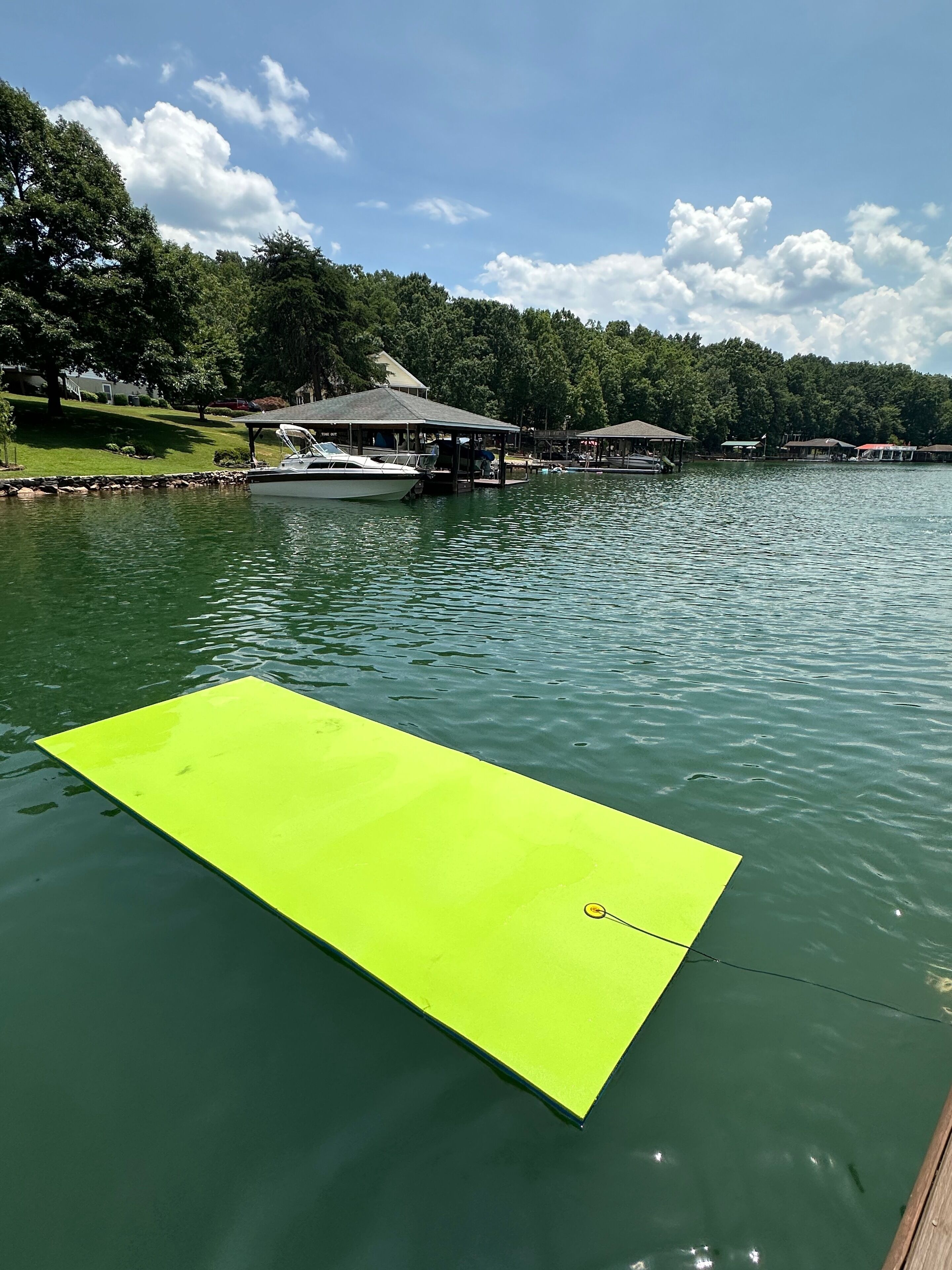 A dock with a boat and a bright yellow floating platform in the water.