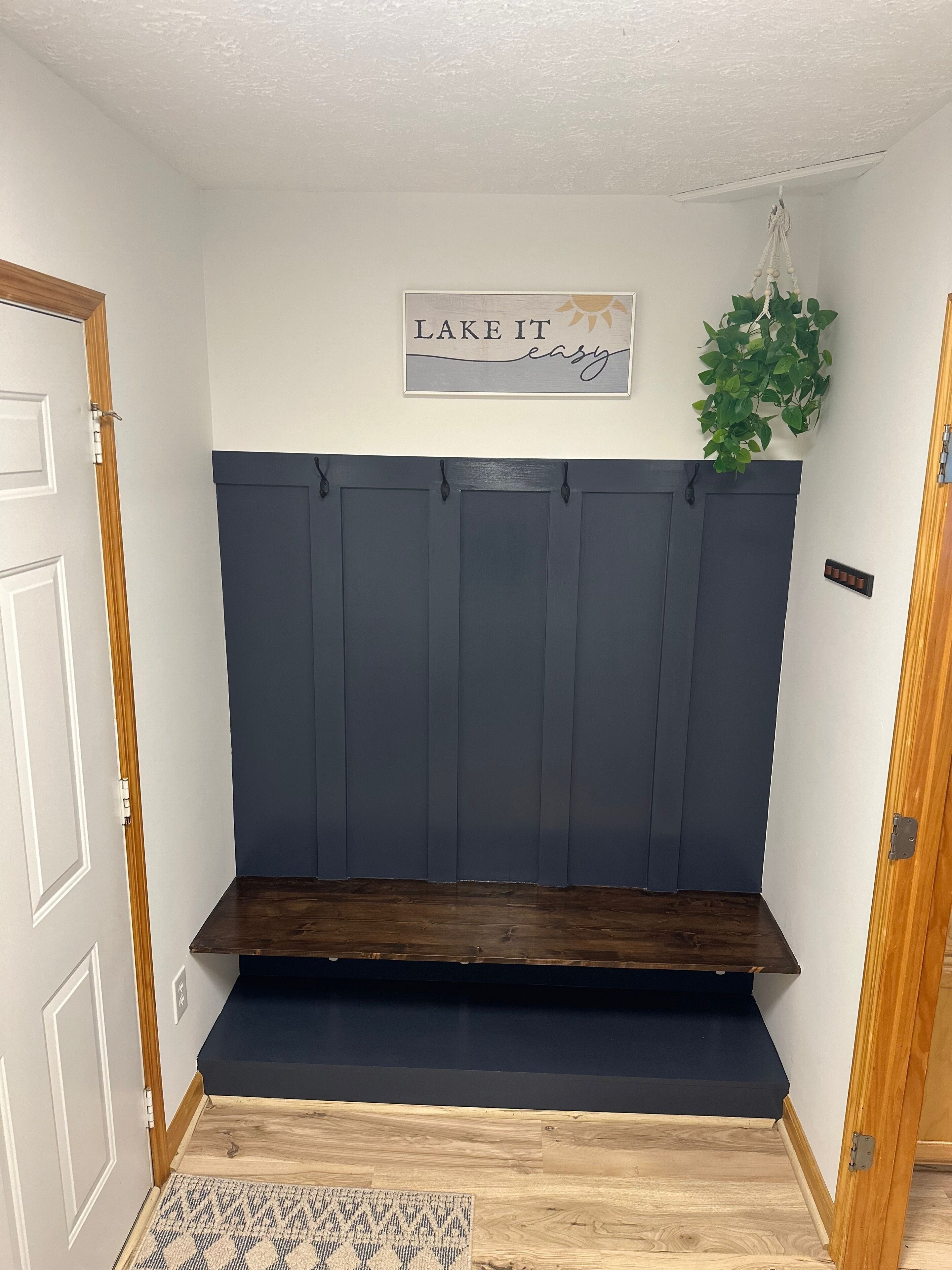Ein Zimmer mit einer dunkelblauen Bank, einem an der Wand befestigten Schild mit der Aufschrift „LAKE IT easy“ und einer hängenden Pflanze.