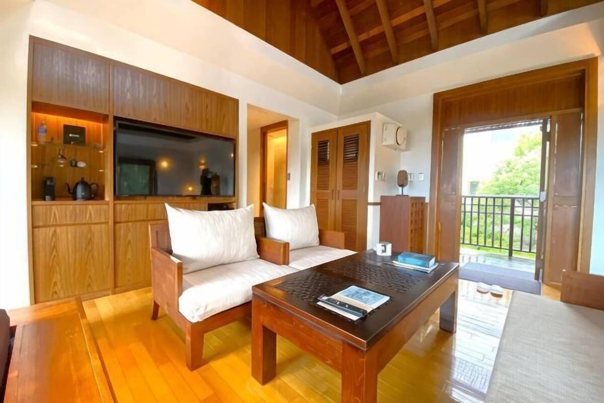 Une pièce comprenant un canapé en bois, une table basse, un téléviseur et un balcon avec vue.