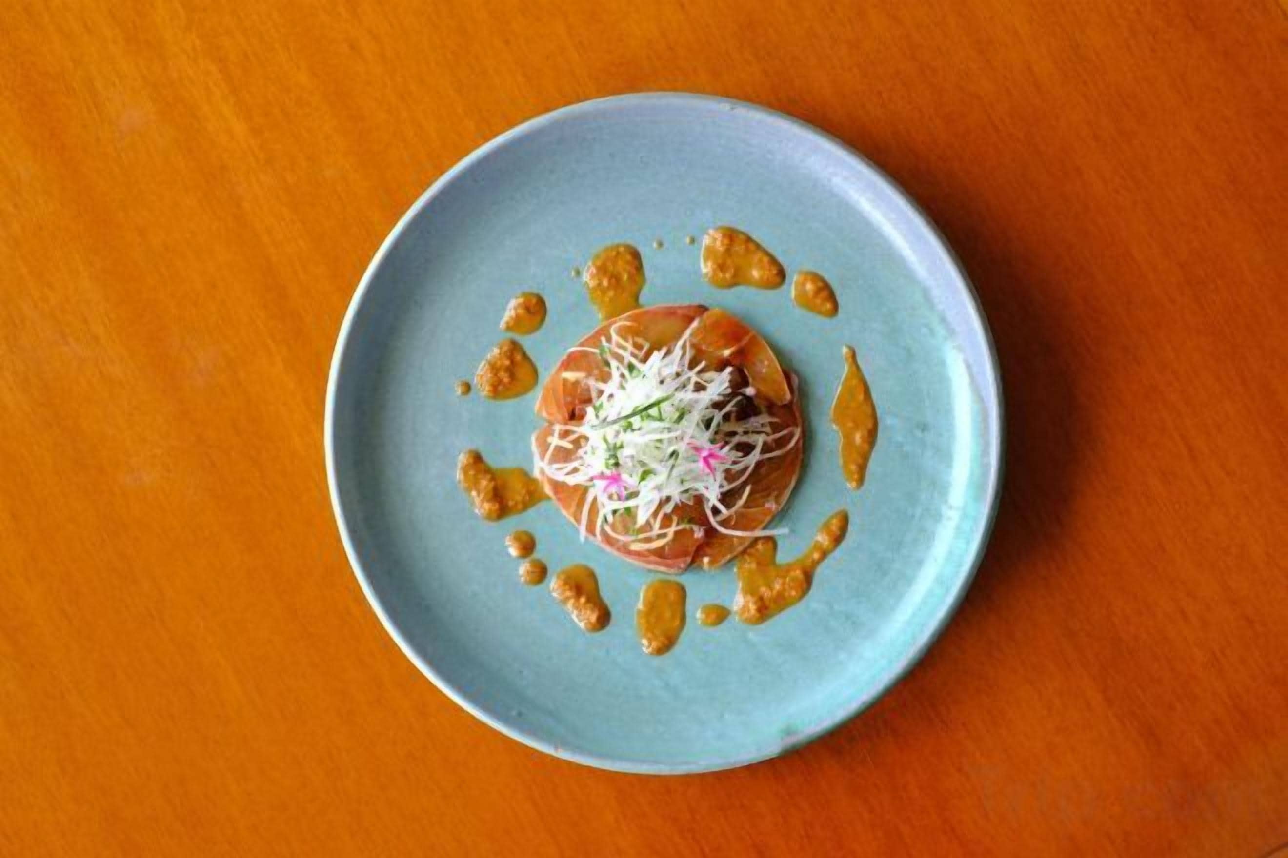 A plate with food on a blue plate on a wooden surface.